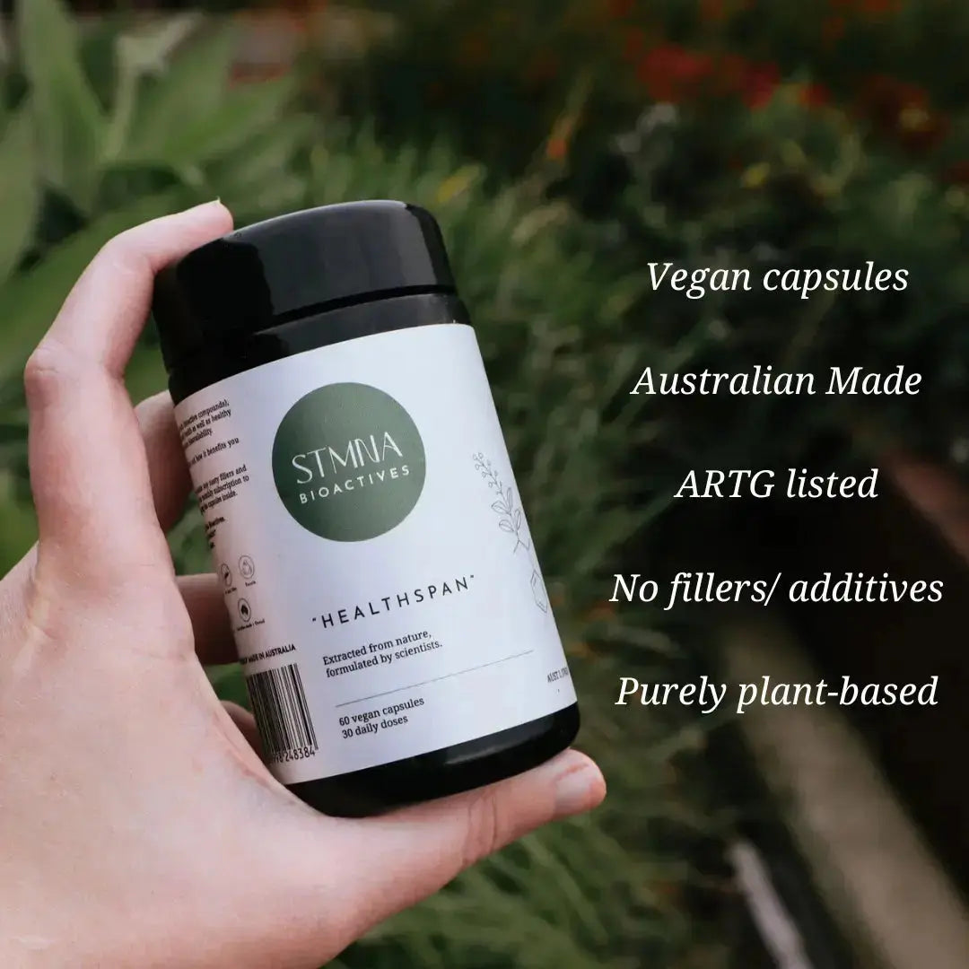 Hand holding a jar of 'STMNA Bioactives' vegan capsules with text highlighting features.