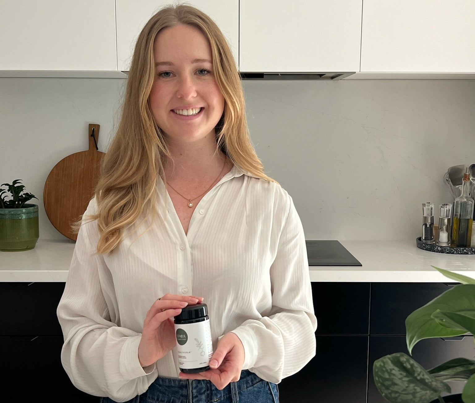 Holly holding Healthspan supplement in a kitchen