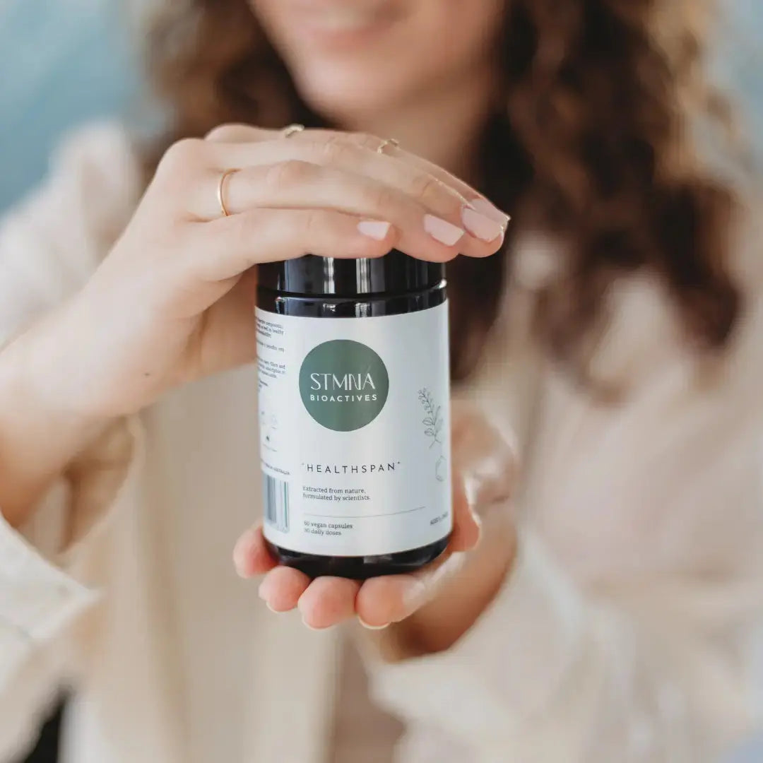 Person holding a STMNA Bioactives Healthspan supplement jar
