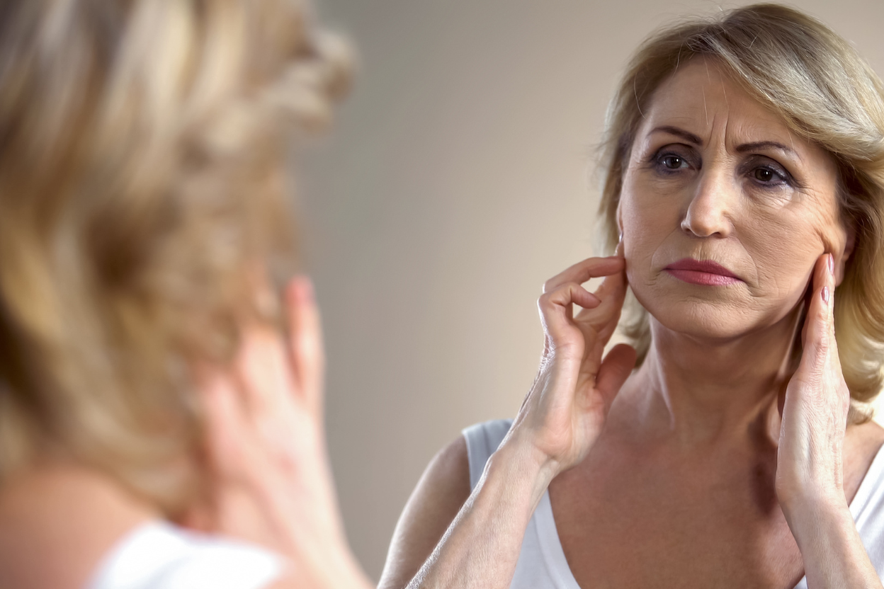 Woman looking at her self to see the effect of aging without longevity supplements